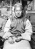 Buyan-Badyrgy, wearing traditional Tuvan dress, sitting expressionless