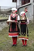 Two girls dressed in traditional costume wish a traditional welcome with bread and salt to the guests in the village of Konopnica, North Macedonia.