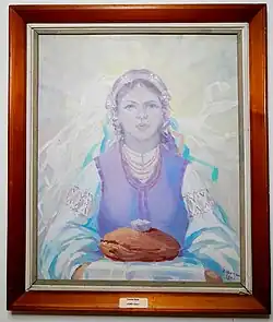 A woman in traditional Ukrainian dress holding a loaf of bread​​‌