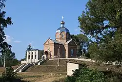A church atop a small hill with trees visible at each side of the photograph.