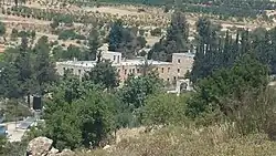 A landscape image showing a view from southeast of the Beracah valley, featuring a building surrounded by greenery and hills, relevant to the historical and biblical significance of the area as described in the Second Book of Chronicles.
