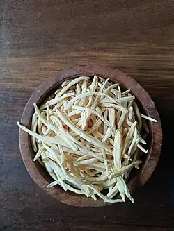 Dried safed musli roots in a wooden bowl, used in Ayurvedic medicine.