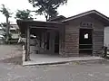 A white horse outside a wooden stable.