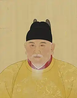 The Hongwu Emperor has a white beard and wears a yellow robe and a black cap.