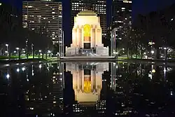 Photograph of a large memorial building at night. The building is being reflected in a body of water in front of it.