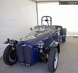 A blue, vintage-styled car sitting in a grey garage.