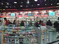 A newsstand showing many magazines. There are TVs showing the news in the background.