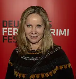 Ann-Kathrin Kramer wearing a dark patterned sweater, grinning directly at camera