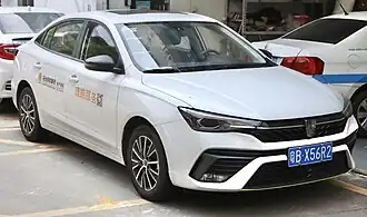 A small front-engined four-door car with a three-box design with alloy wheels, door mirrors, a front grille, stylised headlights, front fog lamps, and a sunroof.