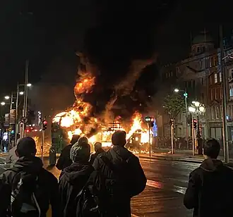 A Dublin Bus burning in front of the monument during the 2023 Dublin riot
