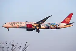 An airliner from China's Juneyao Airlines in flight, which contains a Genshin Impact-themed collaboration livery.