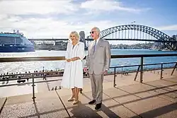 Charles and Camilla standing in front of a bridge