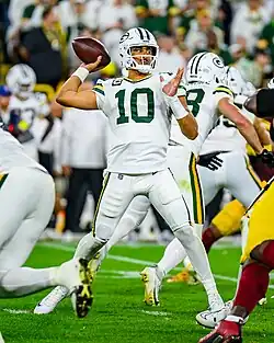 Love on a football field in his uniform during a game, throwing a football