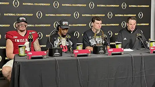 Football players and coaches giving a press conference
