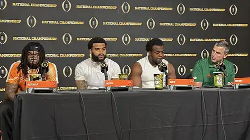 Football players and coaches giving a press conference