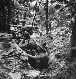 Soldiers in slouch hats occupy a defensive position in a jungle clearing