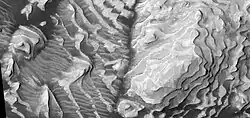 Close, color view of layers and dark dust on floor, as seen by HiRISE. Some small faults are visible in image.