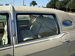Closeup image of rear roofline of a 1977 Lincoln Continental Town Car, showing padded rear vinyl roof and opera windows