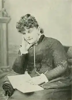 19th-century B&W portrait photo of a woman with her hair in an up-do, wearing a dark, fitted blouse.