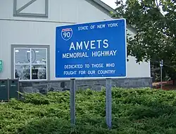 A blue sign with the I-90 sign and "AMVETS Memorial Highway"