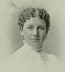 B&W portrait photo of a woman with her hair in an up-do, wearing a white, high-collared blouse