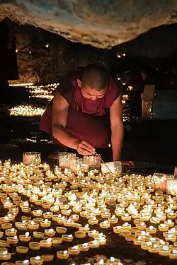 A Tibetan pilgrim lighting ghee lamps in a sacred cave on the Tibet plateau