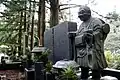 A statue of a deceased pilgrim at his grave site in Okunoin Cemetery