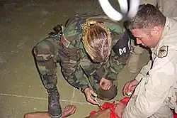 Image 1US Military Police officer restraining and sedating prisoner while a soldier holds him down (from Political corruption)