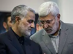 Two men, gray hair and beards, exchanging in low voices