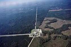 An aerial view of a large building complex partially in a forest, with roads extending into the forest.