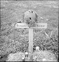 Wooden cross on grave with a steel helmet on top of cross