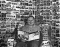 Albert K. Bender sitting on chair reading magazine
