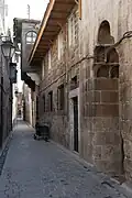 Street in the Farafira quarter leading to the entrance portal of the Khanqah al-Farafira; features traditional Islamic architecture, muqarnas, and oriental motifs.