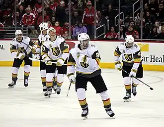 Five ice hockey players warming up before a game, facing the camera.