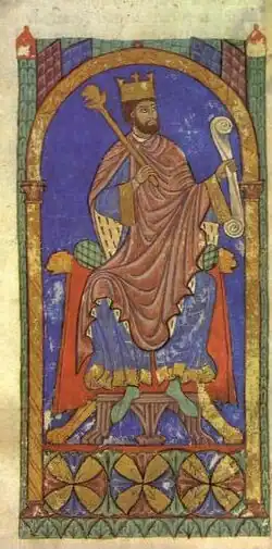 A bearded man wearing a crown sitting on a throne