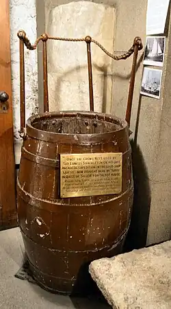 A color photograph of a brown wooden barrel-like structure on display at a museum