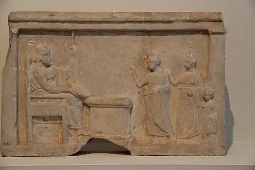 Attic votive relief from the 4th century BC, dedicated to either Zeus Philios or Meilichios. It shows a woman kneeling to him and a ram being sacrificed.[14]
