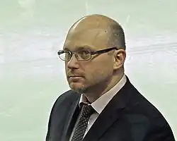 Middle-aged man with balding head, wearing eyeglasses, and dressed in a suit and tie