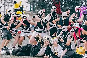 More than a dozen people dressed up to resemble members of Team Skull; some have colored hair, and two resemble the leader, Guzma. Plushes of various Pokémon are also featured, including Pikachu, Yveltal, Psyduck, and Gengar.