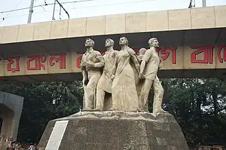 Eight stone figures stand in a circle, arms linked, depicting students in solidarity and protest