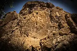The relief is located on the top of a cliff towering over the village of Sarpol-e Zahab. A second relief from the Parthian Empire period appears below.