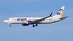 A white jet airliner with purple accents against a blue sky