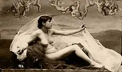 Black and white photograph of a nude female figure in classical pose