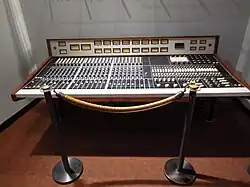 Large mixing board with wood trim behind a velvet rope