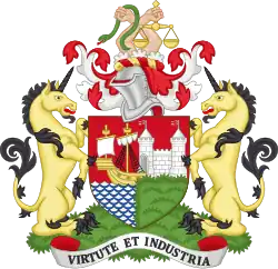 A coat of arms, with a shield showing a sailing ship and a castle with maned lions on either side, surmounted by the helmet from a suit of arms and two hands holding a snake and scales of justice. The motto at the bottom is "Virtute et Industria"