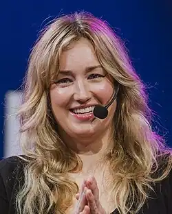 A blonde woman in her early forties smiles at something off-camera