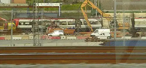 Remains of a commuter train being dismantled by a crane