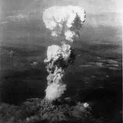 A black-and-white photo of a massive mushroom cloud over Hiroshima, taken from a flying aircraft