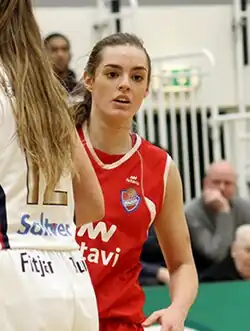 Auður Íris Ólafsdóttir playing basketball during a match, wearing a red jersey.