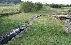 Color photograph of an ancient drainage channel at its exit from a building.